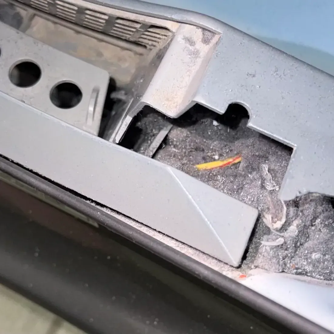 Dryer lint trap housing cavity opened showing packed gray lint beneath the screen